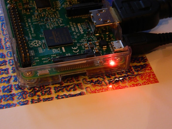 A Raspberry Pi computer sitting atop a glossy, colorful digital screen print